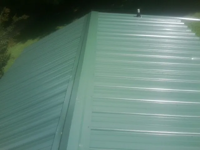 New green metal panels meeting at the ridge of a roof — Flat Roof Repair work by our crew in Fort Campbell