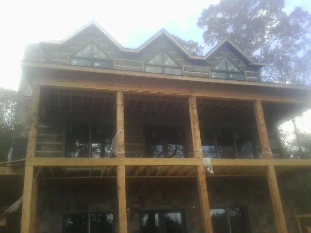 Dormers and porch framing on a large log home under construction — Roof Coating work by our crew in Fort Campbell