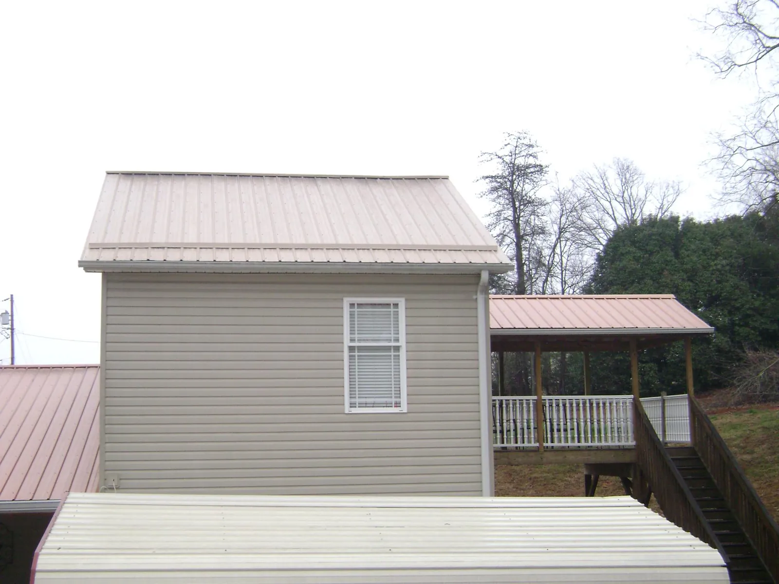 Tan metal roofs on a two story addition and attached porch, from a Roof Replacement job in Fort Campbell