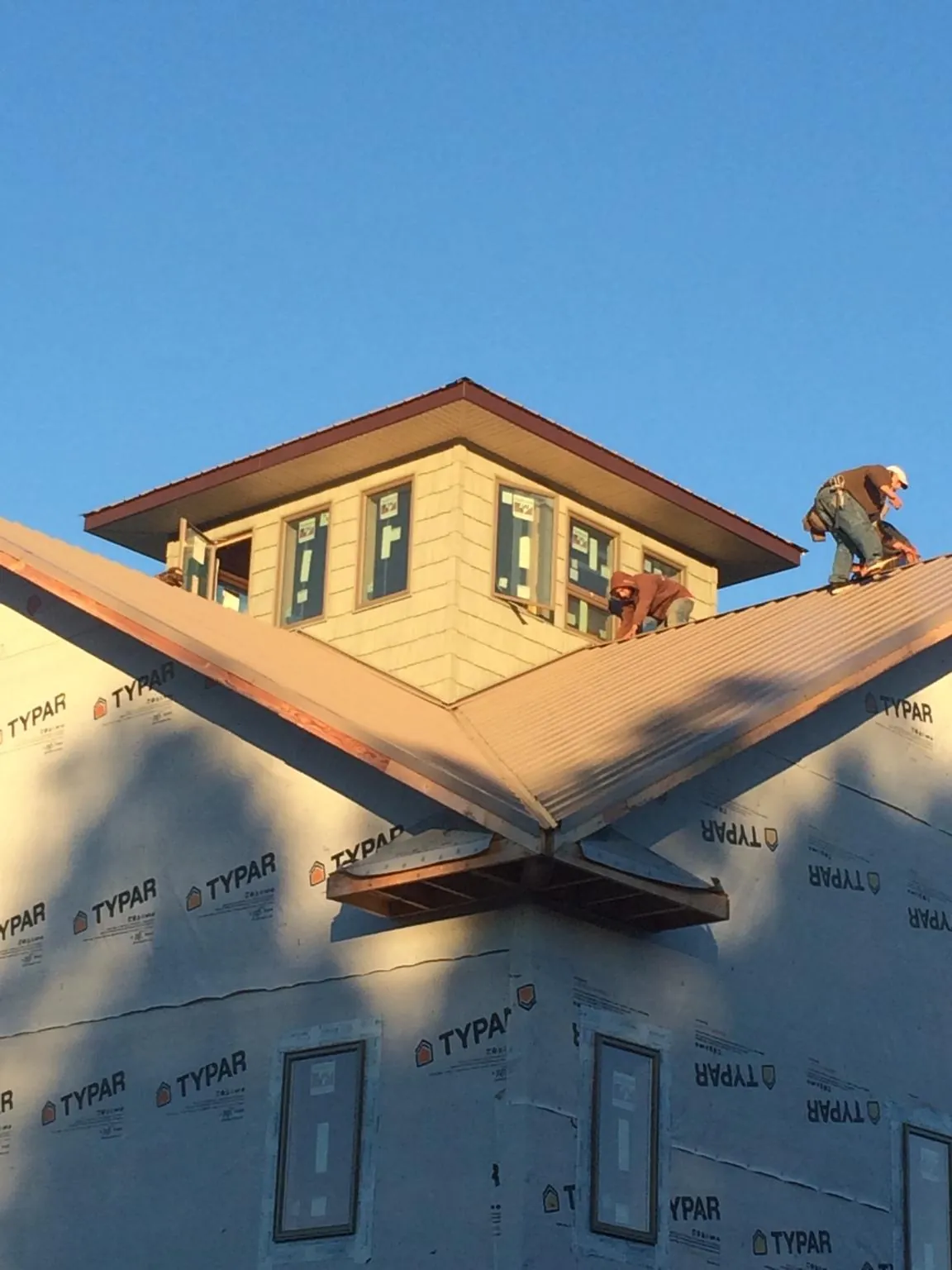 Roofers working around a rooftop cupola on a new metal roof at sunset — Roof Waterproofing in Fort Campbell by Roofing Brothers
